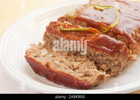 Hausgemachte frische gebackene Fleischkäse belegt mit einer Scheibe grüner Paprika und ein Ketchup basierende Sauce. Stockfoto
