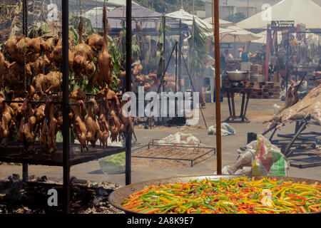 Eine große Pfanne mit Paella vor einer Menge wäscheleinen von Fleisch, mit Enten, Hühner und Rippen Stockfoto