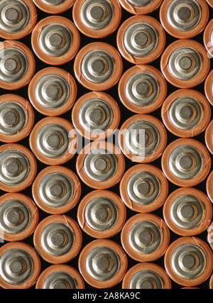 Hintergrundhintergrund der Batteriesäulen mit positiver Seite nach oben. Mehrere Akkus werden zu einem organisierten vertikalen Muster zusammengestapelt. Stockfoto