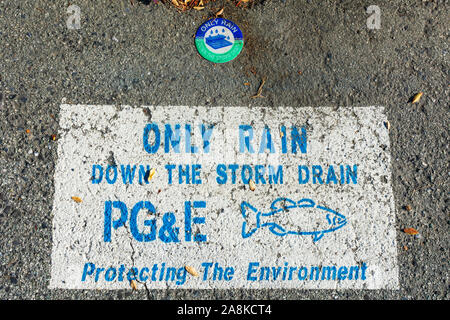 Nur Regen, nach unten zu sturmabfluß Warnschild PG&E, Pacific Gas und Electric Company, in der Nähe der Straße entleeren Einlass. Fisch Silhouette. Schutz der Umwelt Stockfoto