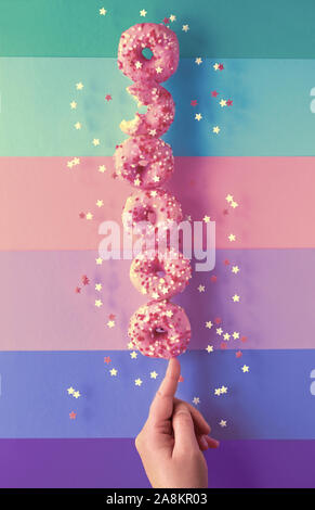 Kreative Bild der vollkommenen Balance, zen wie Turm oder Pyramide an leckeren süßen Rosa donuts Balancieren auf Zeigefinger der weiblichen Hand. Konzeptionelle equilibr Stockfoto