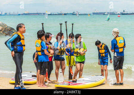 Gruppe von Männern und Frauen die Windsurfer am Strand in Diskussion Stockfoto