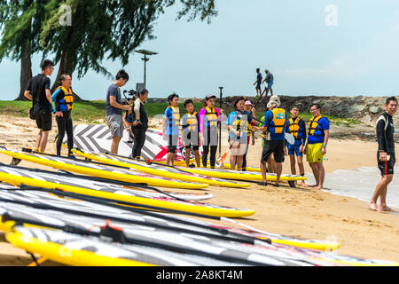 Gruppe von Männern und Frauen die Windsurfer am Strand in Diskussion Stockfoto
