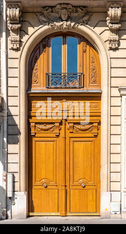 Paris, eine alte Holztür, mit einem auf dem Türsturz gehauenen Kopf, typisches Gebäude im Marais Stockfoto