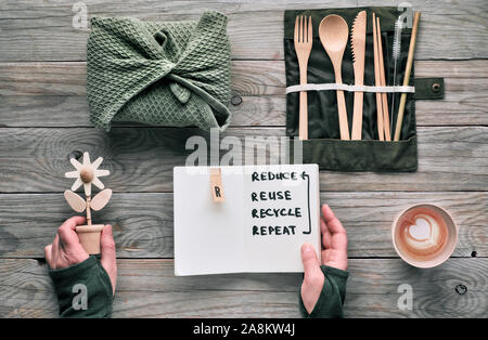 Flach, null Abfall Lunchpaket mit Holz- Utensilien in Textil-, Kaffee in wiederverwendbare Kaffeetasse. Nachhaltiger Lebensstil, Hände halten Text 'reDuce, r Stockfoto
