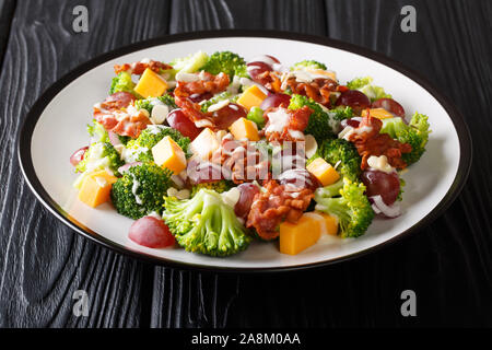 Urlaub Salat mit Brokkoli, Käse, Weintrauben, Speck, Mandeln und Zwiebeln close-up in einem Teller auf dem Tisch. Horizontale Stockfoto