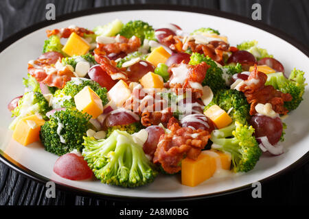 Frischer Salat mit Brokkoli, Cheddar, Trauben, Speck, Mandeln und Zwiebeln mit Creme dressing Close-up in einem Teller auf dem Tisch. Horizontale Stockfoto