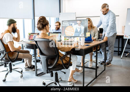 Gruppe von vielfältigen und kreativen Kollegen arbeiten an Computern im modernen Büro oder Coworking Space, Web Design Stockfoto