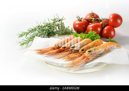 Frische scampi, auch genannt Kaisergranat oder Langustinen, auf einen Teller mit Küchenpapier, Kräuter und Tomaten, bereit, eine exklusive, teure seafoo zu kochen Stockfoto