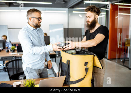 Kurier liefert frische Lebensmittel mit thermischen Tasche für ein büroangestellter. Konzept der Lebensmittel Auslieferung an die Mitarbeiter im Büro Stockfoto