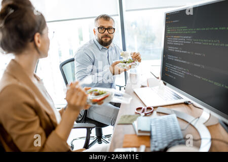 Mann und Frau Salat bei einem Mittagessen Zeit am Arbeitsplatz ohne das Büro zu verlassen Stockfoto