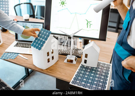 Menschen, die an einem Projekt von alternative Energie, Arbeiten mit Haus Modell und Computer im Büro, close-up auf der Arbeitsfläche Stockfoto