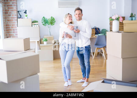 Junge schöne Paar ständigen trinken Kaffee im neuen Zuhause um Kartons Stockfoto