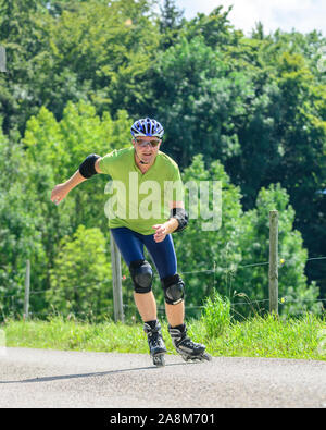 Mann eine skating Tour auf Inline Skates in der grünen Natur Stockfoto
