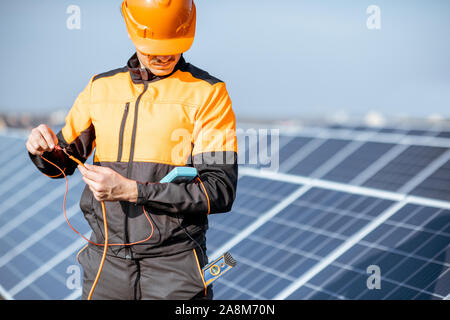 Gut ausgestattete Elektriker Connecting Solar Panels, die Spannung prüfen und anschließen Verkabelung auf einer Photovoltaikanlage auf dem Dach Stockfoto