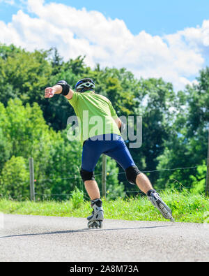 Mann eine skating Tour auf Inline Skates in der grünen Natur Stockfoto