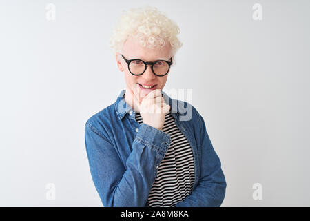 Junge albino blonder Mann tragen Jeanshemd und Gläser über isoliert weißer Hintergrund schaut zuversichtlich in die Kamera lächelnd mit verschränkten Armen und ha Stockfoto