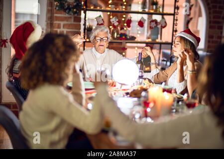 Schöne Gruppe von Frauen Lächeln glücklich und zuversichtlich. Die Hände und betet gemeinsam Weihnachten zu Hause feiern. Stockfoto