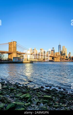 Kiesstrand, Brooklyn Bridge im Morgenlicht, Blick von der Hauptstraße über den East River Park auf die Skyline von Manhattan mit Freedom Tower oder Stockfoto