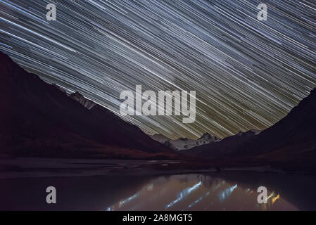 Tolle Nacht mit Sternen in Form von Spuren über die verschneiten Berge, Gletscher und den See im Herbst. Altai, Russland Stockfoto