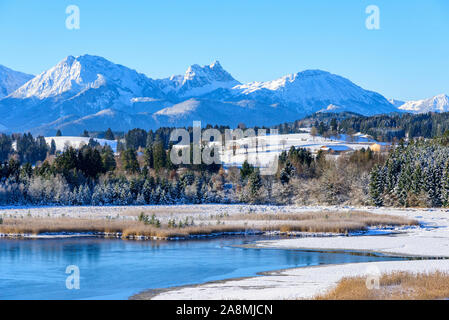 Erster Schnee im Alpenvorland in der Nähe von einem kleinen Teich in bavariain Morgenlicht bei klarem Himmel Stockfoto