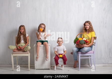 Drei Mädchen und ein Junge, reife Früchte und Gemüse Stockfoto