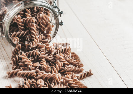 Auf einer weißen Tafel rustikalen Tisch Glas - Italienische Fusilli fliegt aus der Dose Stockfoto