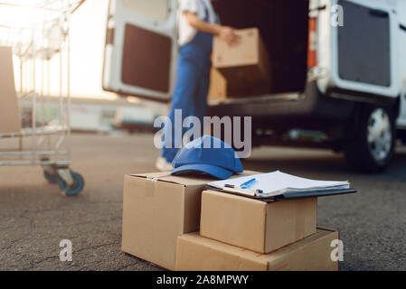 Paketboxen und Kappe, deliveryman auf Hintergrund Stockfoto