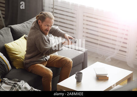 Portrait von frustriert bärtiger Mann vor dem Fernseher zu Hause und versuchen, TV mit Fernbedienung, Kopie Raum Stockfoto