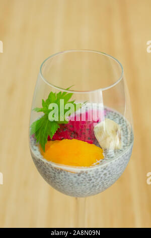 Glas von Chia gesundes Essen Kokos Pudding mit Banane, Mango und Drachenfrucht auf der Bambus Hintergrund. Gesundes Konzept Stockfoto