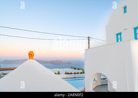 Orange Urne auf Ende der oberen Wand führen auf Horizont und vorgelagerte Insel mit typischen Santorin Architektur. Stockfoto