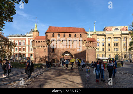 Touristen und Reiseleiter stehen vor der Krakau Barbican an einem sonnigen Herbsttag Stockfoto