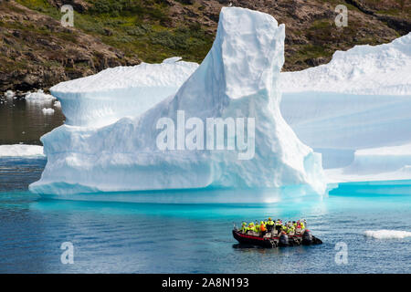 Touristen segeln in kleinen Booten in der Nähe grosser Eisberge von Tunulliarfik Fjord im Sommer. Narsaq, Kujalleq, Südgrönland Stockfoto