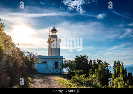 Leuchtturm im Norden der Insel Skopelos, Kavos Gourouni, Griechenland gegen einen tiefen blauen bewölkten Himmel Stockfoto