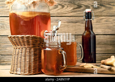 Frische hausgemachte Kombucha fermentierter Tee trinken in Glas mit Hahn und in Dosen - Becher auf Holz- Hintergrund. Stockfoto