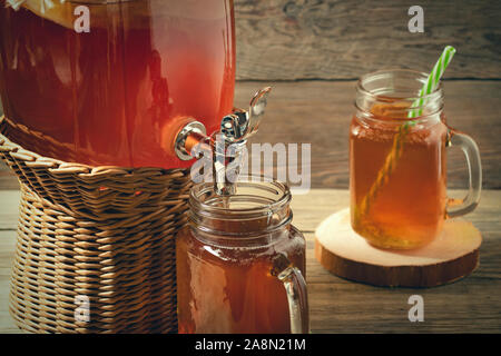 Frische hausgemachte Kombucha fermentierter Tee trinken in Glas mit Hahn und in Dosen - Becher auf Holz- Hintergrund. Stockfoto