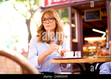 Portraitfotos von lächelnden reife Frau am Tisch sitzen und Kaffee im Café im Freien. Stockfoto
