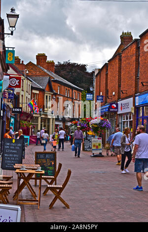 Ein Blick auf die Käufer entlang Pfeffer Street bummeln in der historischen Marktstadt von Nantwich. eine Mischung aus kleinen Geschäften und Cafés. Ziemlich hängenden Blumenkörben. Stockfoto