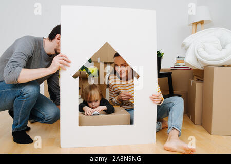 Wenig junge spielt in einem Haus wie Rahmen, von seinen Eltern gehalten Stockfoto