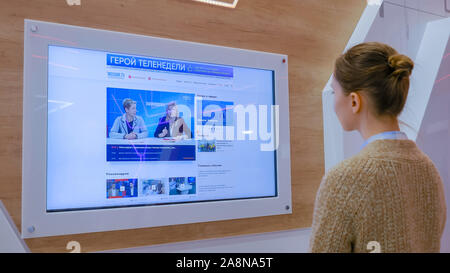 Frau Fernsehen Nachrichten auf interaktive Display Wall Stockfoto
