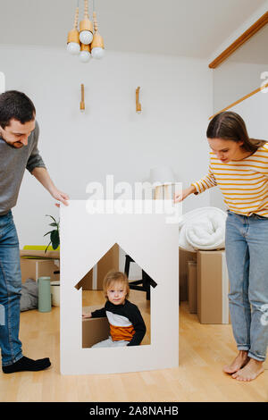 Kleiner Junge sitzt in einem Haus wie Rahmen, von seinen Eltern gehalten Stockfoto