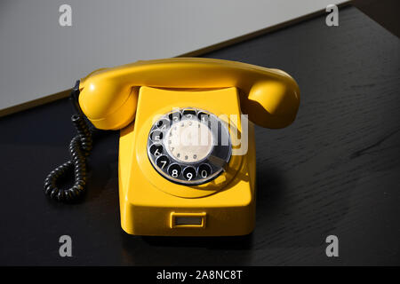 Alten Retro Vintage Gelb Rotary Telefon auf schwarzem Holz Tisch Stockfoto