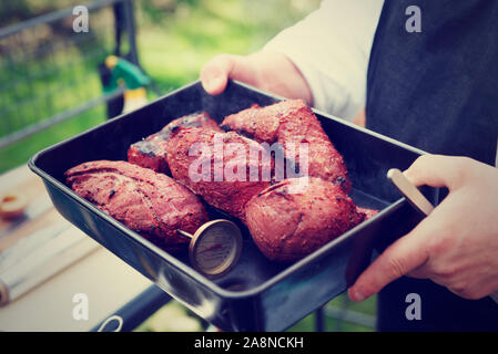 Koch Holding ein Fach mit gekochtem Fleisch, Außenaufnahme, getönten Bild Stockfoto