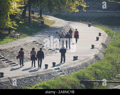 Menschen zu Fuß auf Riverside Promenade an der Raab Fluss an einem sonnigen Herbsttag in Győr, Ungarn Stockfoto