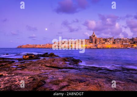 Stadt Valletta in Malta, abendliche Skyline Blick auf das Meer von der Insel Manoel felsigen Ufer. Stockfoto