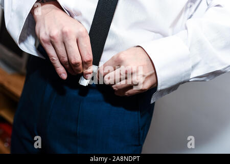 Ein Mann, der Bräutigam auf seine Hosenträger, ihnen Beulen an seiner Hose auf seinen Hochzeitstag. Formelle Kleidung, Stylistin und elegant, Befestigung Stockfoto