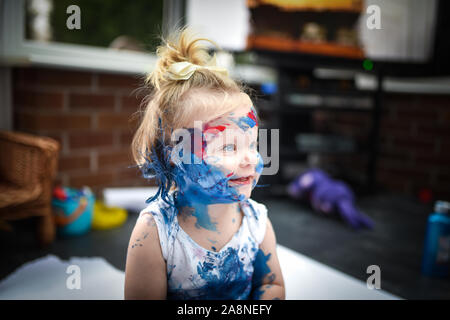 Eine entzückende kleine Kleinkind, Mädchen hat Spaß beim Spielen mit Farben malt, unordentlich und haben viel Spaß, in einer familiären Umgebung Schuß Stockfoto