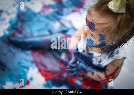 Eine entzückende kleine Kleinkind, Mädchen hat Spaß beim Spielen mit Farben malt, unordentlich und haben viel Spaß, in einer familiären Umgebung Schuß Stockfoto