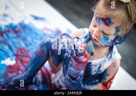 Eine entzückende kleine Kleinkind, Mädchen hat Spaß beim Spielen mit Farben malt, unordentlich und haben viel Spaß, in einer familiären Umgebung Schuß Stockfoto