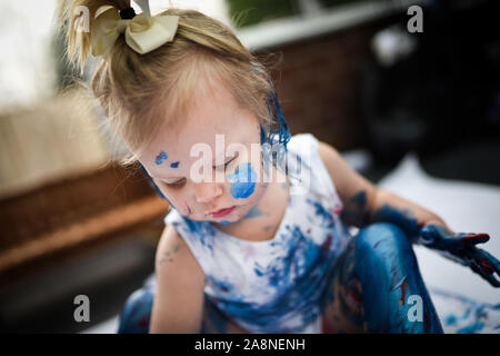 Eine entzückende kleine Kleinkind, Mädchen hat Spaß beim Spielen mit Farben malt, unordentlich und haben viel Spaß, in einer familiären Umgebung Schuß Stockfoto